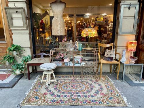 A cozy storefront display featuring vintage furniture, a decorative rug, and eclectic decor items.