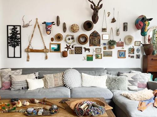 A cozy living room with a gray sofa adorned with various pillows, and a gallery wall of eclectic art and decor.