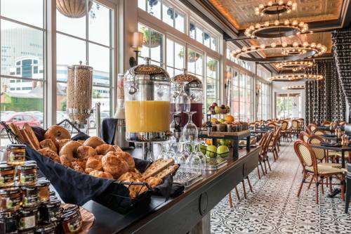 A stylish café interior featuring a variety of pastries, drinks, and elegant decor with large windows and seating.