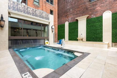 A modern outdoor pool area with a water feature, surrounded by brick walls and greenery.