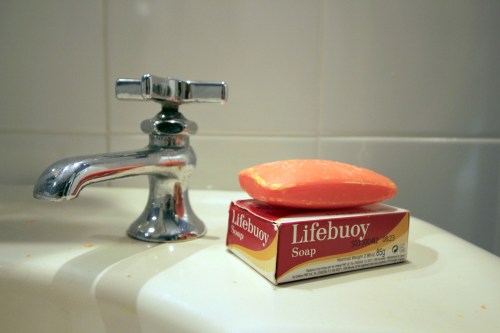 A bar of Lifebuoy soap sits on a sink next to a shiny faucet in a bathroom setting.