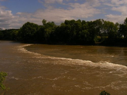 A winding river flows through a lush green landscape under a partly cloudy sky.