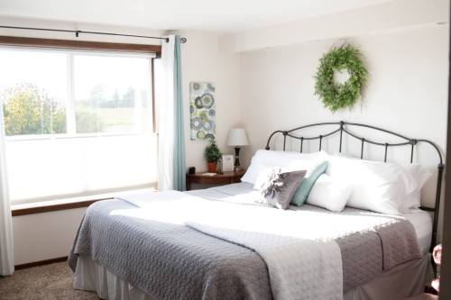 Bright, cozy bedroom with a large window, a neatly made bed, and decorative wall art.