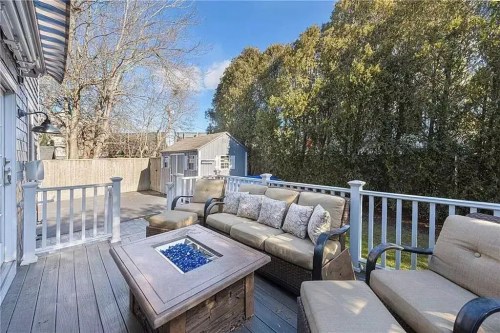 A cozy outdoor deck with a seating area and a fire pit, surrounded by trees and a fenced yard.