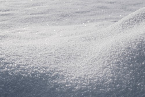 Close-up of a smooth, sparkling snow surface, glistening in the sunlight.