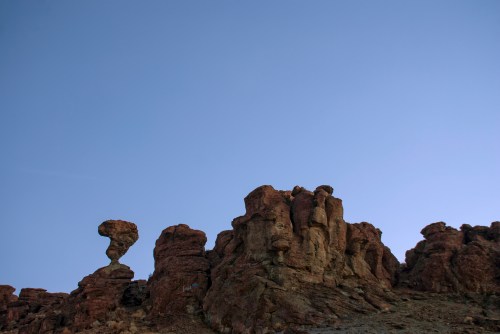 Rock formations against a clear blue sky, featuring a distinctive balancing rock on the left.