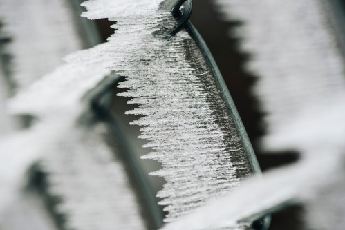 Close-up of icy frost forming on a metal surface, creating a textured, crystalline pattern.
