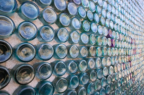 A close-up of a wall made of various glass bottles arranged in a mosaic pattern.