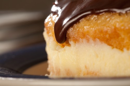 Close-up of a dessert slice with a creamy layer topped with glossy chocolate ganache.