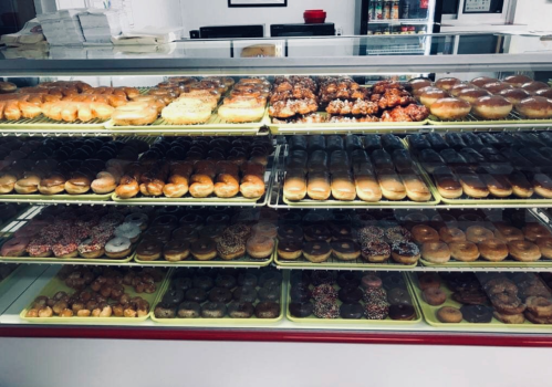 A display case filled with a variety of colorful donuts, including glazed, chocolate, and sprinkled options.