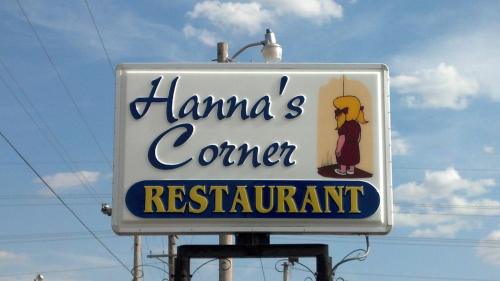 Sign for "Hanna's Corner Restaurant" featuring a cartoon girl and a blue sky with clouds in the background.