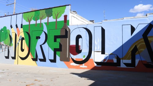 Colorful mural featuring the word "NORFOLK" with trees, a wine bottle, and abstract designs in the background.
