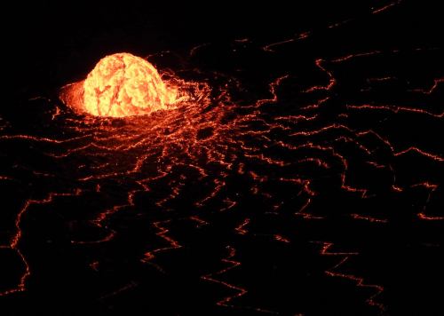 Lava bubbling and flowing from a volcanic crater, glowing bright orange against a dark background.