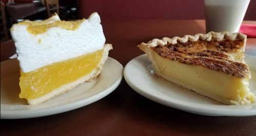 Two slices of pie on plates: one with lemon filling and meringue topping, the other with a creamy custard filling.