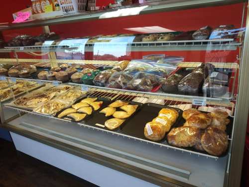 A display case filled with various baked goods, including cookies, pastries, and brownies, in a bakery setting.
