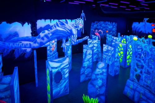 A vibrant, neon-lit maze with underwater-themed structures and a large, glowing creature suspended above.