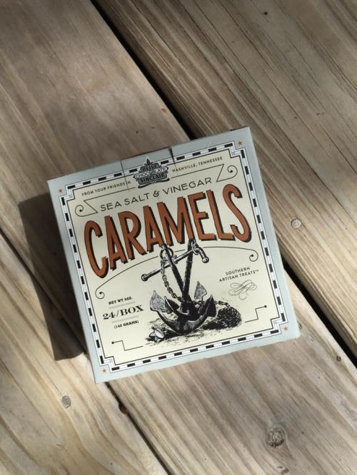 A box of sea salt and vinegar caramels on a wooden surface, featuring vintage-style packaging and an anchor design.
