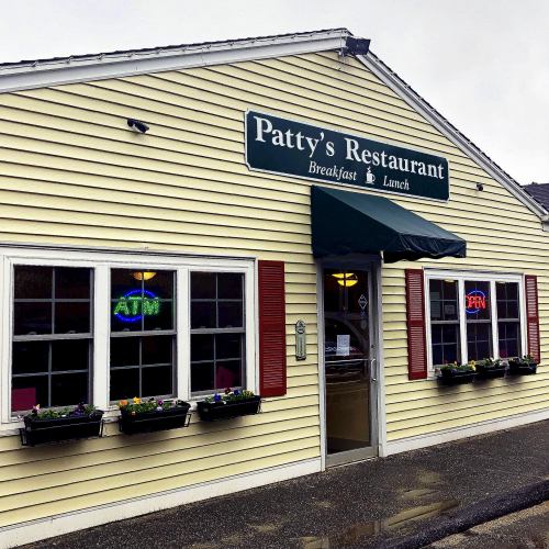 Exterior of Patty's Restaurant, featuring a green awning, flower boxes, and signs for breakfast and lunch.