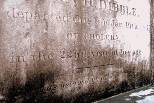 Weathered gravestone inscription detailing the death of a person named H. Dibble from cholera at age 22.