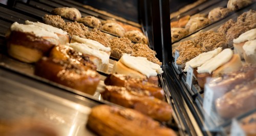 A display case filled with various baked goods, including frosted pastries and muffins.