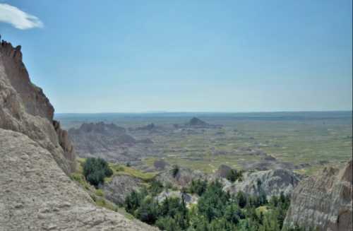 A panoramic view of rugged rock formations and green valleys under a clear blue sky.