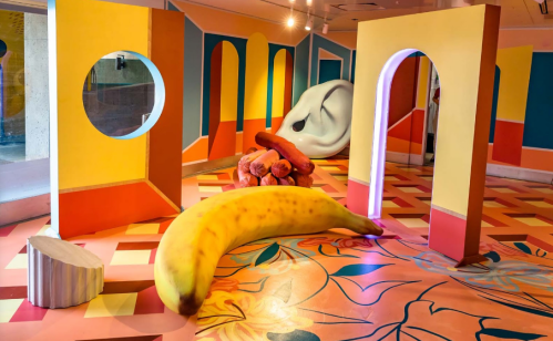 Colorful art installation featuring oversized fruit and abstract shapes in a vibrant, playful environment.
