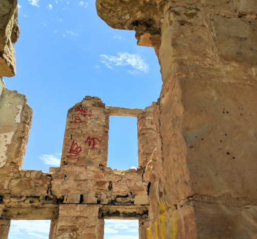 Ruins of a stone structure with graffiti, under a clear blue sky.