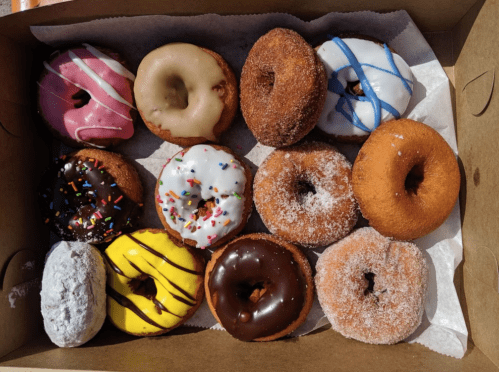 A box of assorted donuts, featuring various toppings like sprinkles, icing, and powdered sugar.