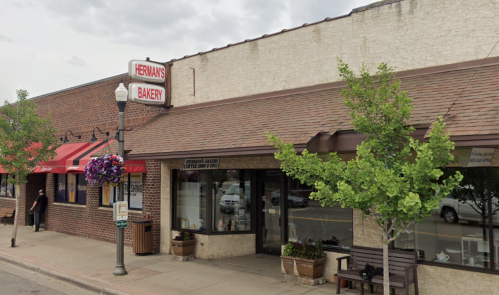 Exterior of Hernan's Bakery with a sign, awning, and planters, located on a street with pedestrians and parked cars.