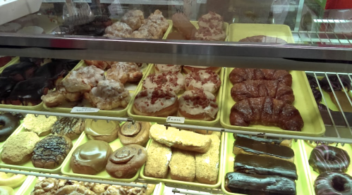 A display case filled with various pastries and donuts, including glazed, chocolate-covered, and cream-filled options.