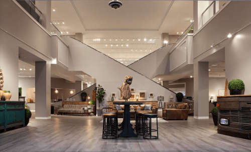 Modern interior space featuring a wooden table, stools, and stylish decor with a staircase in the background.