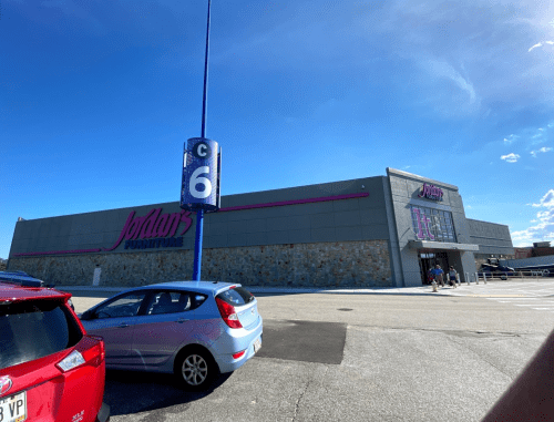 Exterior of Jordan's Furniture store with a clear blue sky and parked cars in the foreground.