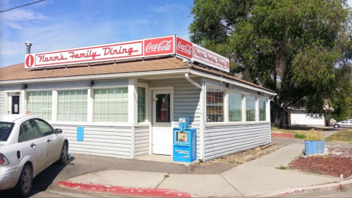 Exterior of Nanna's Family Dining, a cozy restaurant with a Coca-Cola sign, surrounded by greenery and a parking area.