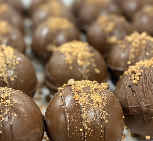 Close-up of chocolate truffles topped with crushed cookies, arranged in a neat row.