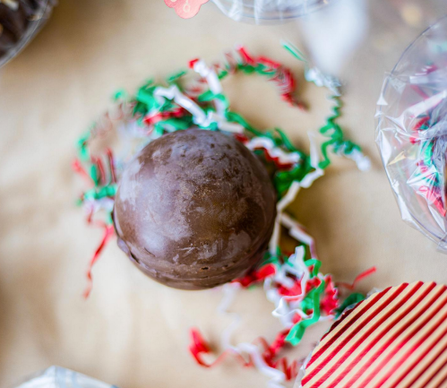 A chocolate sphere surrounded by colorful shredded paper on a festive table.