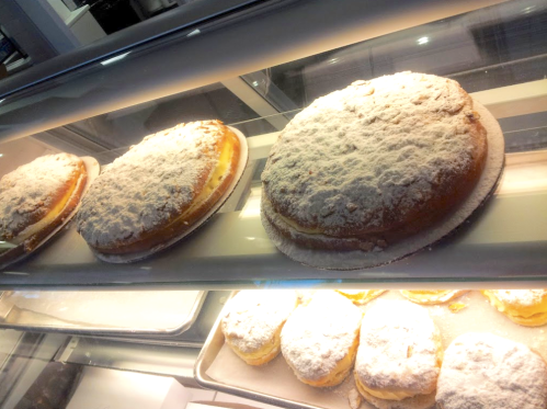 Three round cakes dusted with powdered sugar, displayed in a glass case.