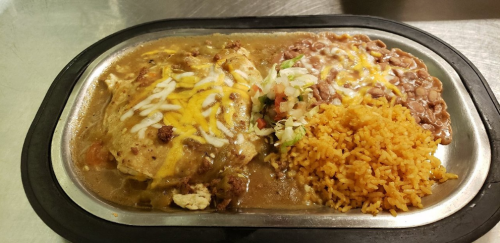 A sizzling platter with chicken smothered in sauce, cheese, rice, refried beans, and fresh toppings.