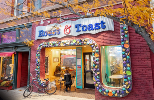 A cozy café called "Roast & Toast" with colorful decor and outdoor seating, framed by autumn leaves.