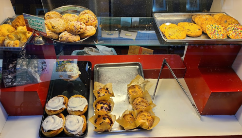 A display case filled with various baked goods, including cookies, pastries, and muffins.