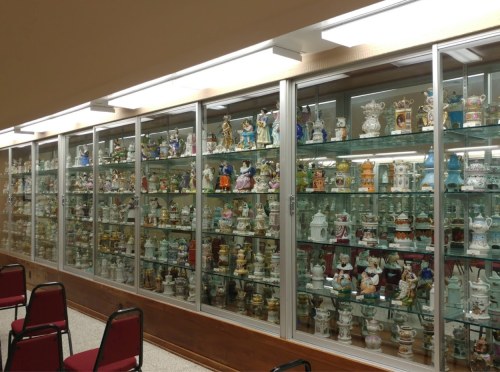 A display case filled with various colorful porcelain figurines and decorative items, arranged neatly on shelves.
