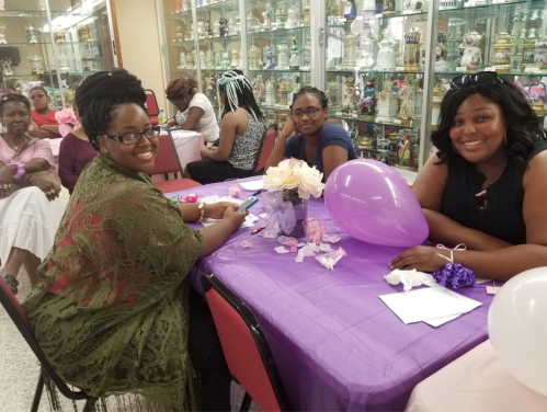 A group of women at a decorated table with purple accents, enjoying a gathering and engaging in conversation.