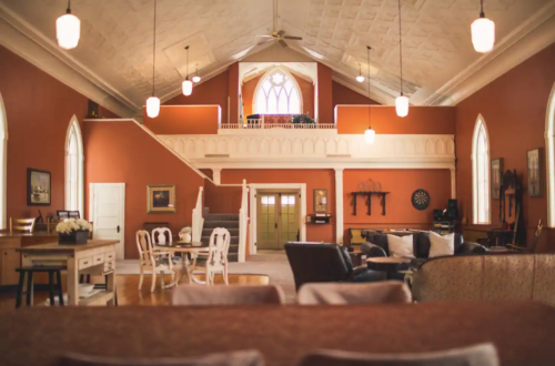 Spacious, elegantly designed living room with high ceilings, large windows, and warm orange walls.