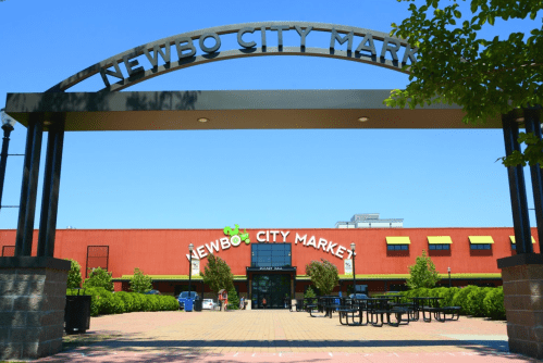 Entrance to Newbo City Market, featuring a large archway and colorful building under a clear blue sky.