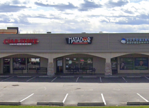 A storefront with three businesses: Cold Stone Creamery, Matador, and Tutoring Excellence, under a cloudy sky.
