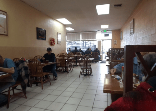 A cozy diner interior with wooden chairs and tables, featuring patrons enjoying their meals in a relaxed atmosphere.