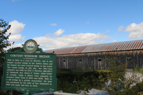 Historic Cornish-Windsor Bridge, the longest wooden covered bridge in the U.S., with a green informational sign.