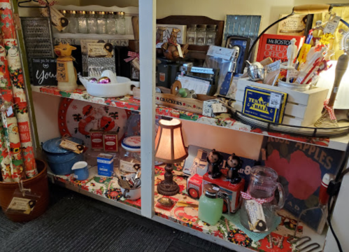 A display shelf filled with vintage items, jars, kitchenware, and decorative pieces, all arranged with festive decor.