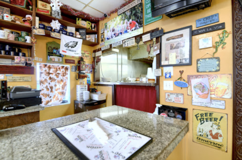 Cozy restaurant interior with a counter, menu, and colorful wall decor featuring signs and memorabilia.