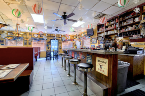 Cozy diner interior with a bar, festive decorations, and booths, featuring a warm, inviting atmosphere.