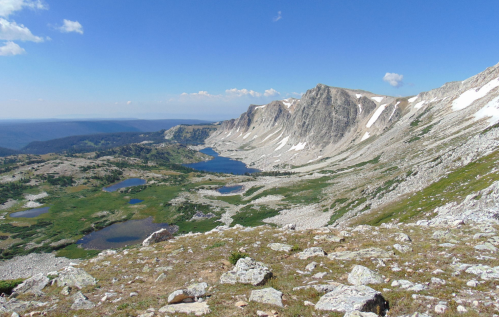 A panoramic view of a mountainous landscape with lakes, rocky terrain, and clear blue skies.